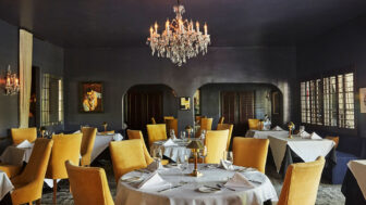 Elegant dining room at the Ingleside Estate Hotel with yellow chairs, chandelier, and stylish decoration.